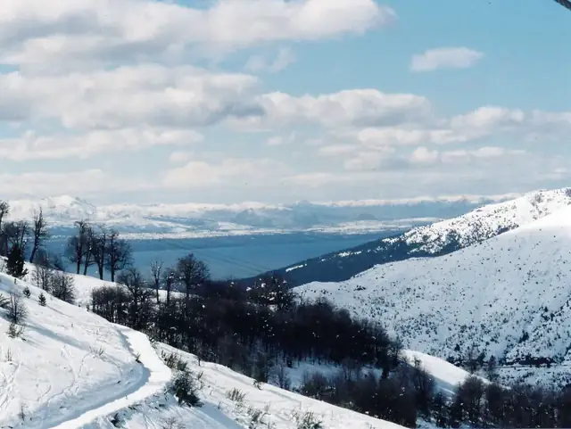 Montanhas cobertas de neve com lago ao fundo